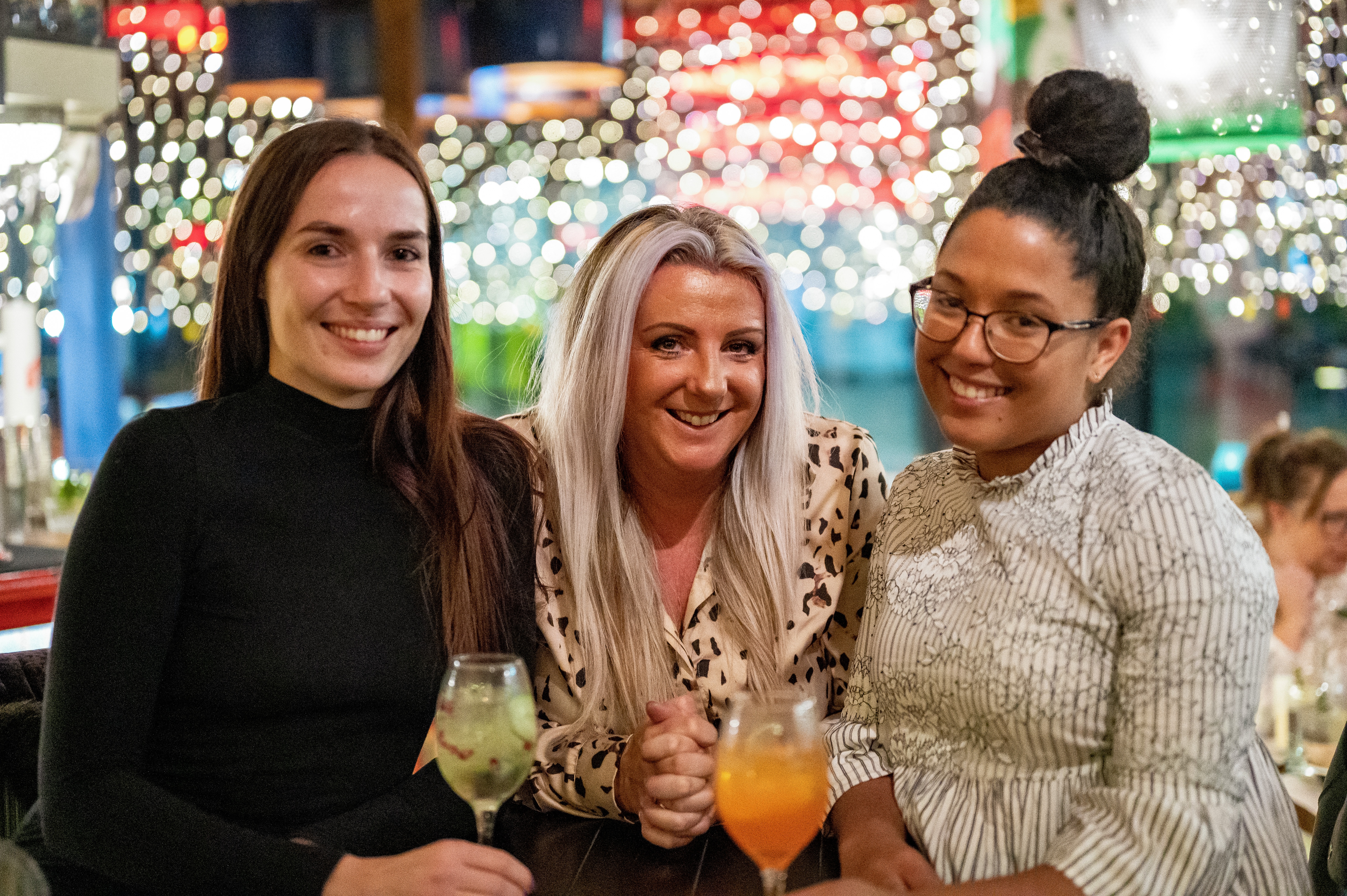 3 girls smiling with cocktails